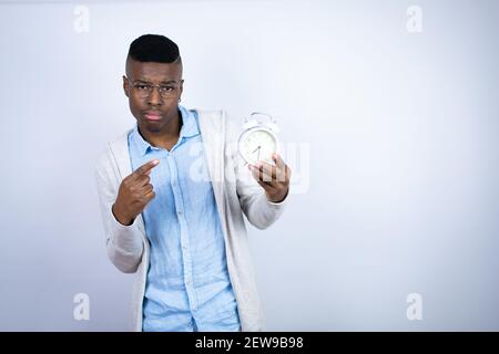Junger schöner afroamerikanischer Mann trägt Freizeitkleidung überrascht halten Und eine Uhr zeigen Stockfoto