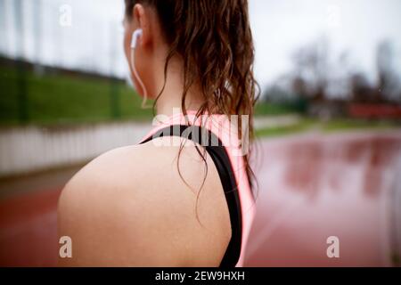 Nahaufnahme der Schulter einer athletischen Frau im Stehen auf der Laufstrecke. Stockfoto