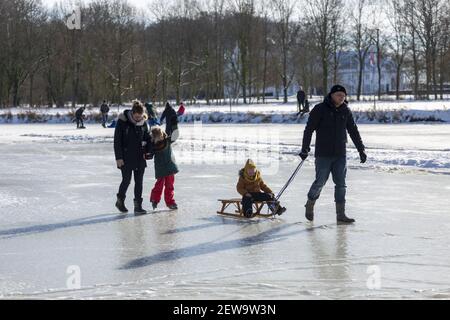 ZUTPHEN, NIEDERLANDE - 14. Feb 2021: Vierköpfige Familie in Winterlandschaft Wandern und Eislaufen auf gefrorenem Fluss Berkel Stockfoto