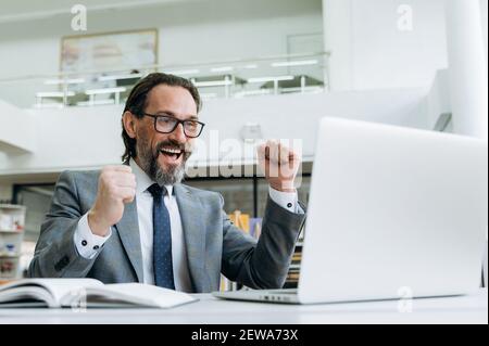 Fröhlicher älterer Geschäftsmann bekam Jobförderung oder ein gutes Geschäft. Erfolgreiche männliche Mitarbeiter so aufgeregt über gute Nachrichten, gut gemacht mit wichtigen Projekt, erhalten großen Gewinn Stockfoto