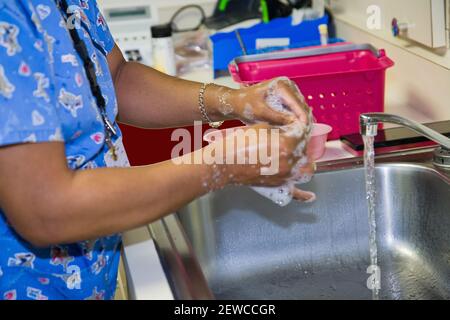 Afroamerikanische Krankenschwester Frau waschen ihre Hände in einem Edelstahl Sinken Sie in einem Krankenhaus oder einer medizinischen Klinik Stockfoto