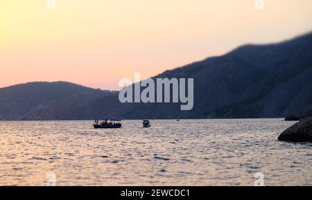 Ein Ausflugsboot in einer ruhigen Bucht des Schwarzen Meeres im Licht der untergehenden Sonne. Stockfoto