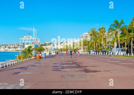 Touristen und lokale Französisch joggen und spazieren entlang der Promenade des Anglais, entlang der französischen Riviera, Cote d'Azur an einem Sommertag. Stockfoto