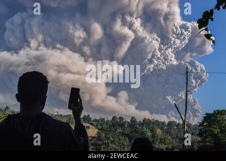 Peking, Indonesien. März 2021, 2nd. Ein Mann nutzt sein Handy, um vulkanische Materialien zu erfassen, die vom Berg Sinabung in Karo, Nord-Sumatra, Indonesien, ausgespuckt wurden, 2. März 2021. Der Berg Sinabung auf der indonesischen Insel Sumatra brach am Dienstag aus und spuckte Aschewolken bis zu 5.000 Meter in den Himmel. Es gab keine Berichte über Verletzte oder Schäden. Kredit: Sarianto Sembriing/Xinhua/Alamy Live Nachrichten Stockfoto