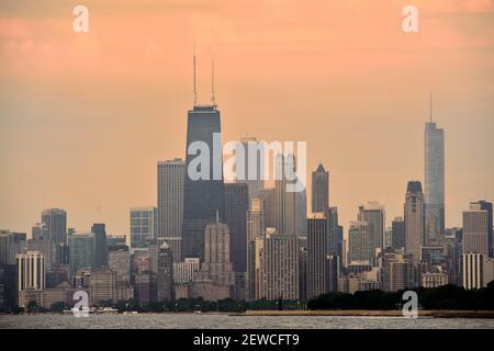 Chicago, Illinois, USA. Ein gedämpfter Sonnenaufgang wirft Licht in die Wolken über einem Teil der Skyline von Chicago und dem Lake Michigan. Stockfoto