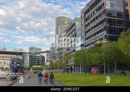 Fußgänger, die auf einem Fußweg zwischen dem Yachthafen der Stadt und den farbenfrohen Wohnhäusern in Melbourne spazieren. Stockfoto