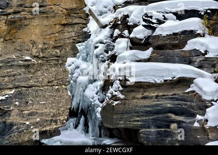 Ein horizontales Bild der Felswände des Athabasca Canyon mit Eis und Schnee, die sich im Winter im Jasper National Park in Alberta, Kanada, an den Felsen Klammern. Stockfoto
