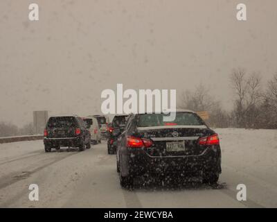 Heftiger Schnee und ein Zuganhänger mit einem Pressmesser auf einer amerikanischen Autobahn, was zu erheblichen Verzögerungen führte. Stockfoto