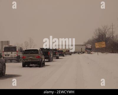 Heftiger Schnee und ein Zuganhänger mit einem Pressmesser auf einer amerikanischen Autobahn, was zu erheblichen Verzögerungen führte. Stockfoto