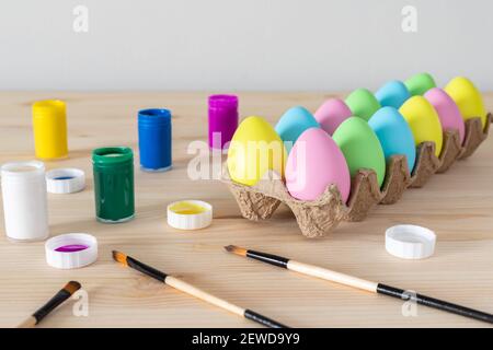 Ostereier und farbige Farben mit Pinsel auf dem Tisch. Osterhandwerk-Konzept. Stockfoto