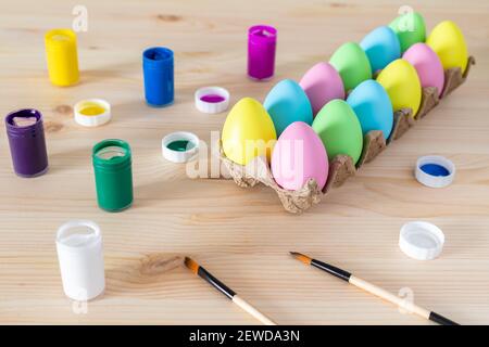 Ostereier und farbige Farben mit Pinsel auf dem Tisch. Osterhandwerk-Konzept. Stockfoto