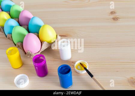 Ostereier und farbige Farben mit Pinsel auf dem Tisch. Osterhandwerk-Konzept. Stockfoto