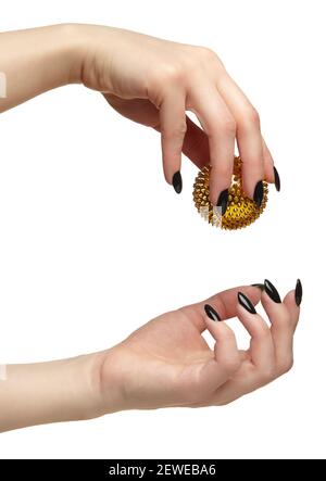 Weibliche Hand mit schwarzen Nägeln Maniküre und goldenen Spikes Massage Ball in den Fingern. Isoliert auf weißem Hintergrund. Stockfoto
