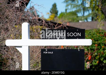 Coming soon Zeichen in der Nähe eines Hauses zum Verkauf in einer Wohngegend. Grüne Bäume Hintergrund. Stockfoto