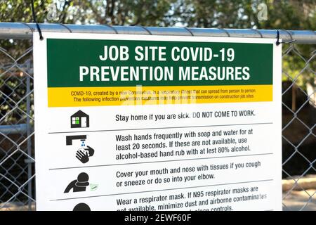 Covid-19 Schild mit Anweisungen auf dem Zaun am Eingang zum Arbeitsplatz. - San Jose, Kalifornien, USA - 2021 Stockfoto