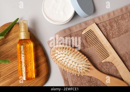 Kosmetik für Körper- und Haarpflege aus natürlichen Inhaltsstoffen. Flat Lay pflegende und feuchtigkeitsspendende Körpercreme, ätherisches Öl, Kamm und flauschiges Handtuch auf gr Stockfoto