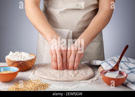 Zubereitung von HauszubereitungTürkisches Fladenbrot, Pide oder Pizzabasis in der Küche. Eine Köchin macht Fingernagel-Eindrücke für die spezifische Traditio Stockfoto