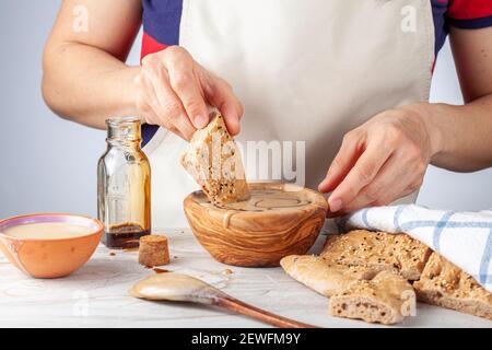 Eine kaukasische Frau mit Schürze taucht türkische Pide ein (Fladenbrot) Mit Sesam und Mohn in traditionelle türkische Tahin Pekmez Wüste hergestellt von Stockfoto