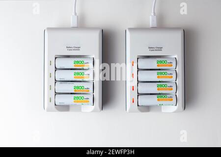 Flachbild von zwei wiederaufladbaren Ladegeräten, die über USB-Kabel mit Strom versorgt werden. Jeder hat einen Stapel von 4 AA-Akkus mit 2800 mAh Kapazität Stockfoto