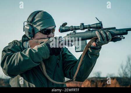 Porträt eines Schützen mit einem Gewehr. Europäer schießt ein Gewehr mit einem optischen Blick Stockfoto
