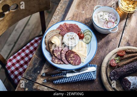 Hoher Winkel von verschiedenen leckeren Wildwurst und Käse Scheiben Mit Roggenbrotstücken und Butter auf Holztisch Stockfoto
