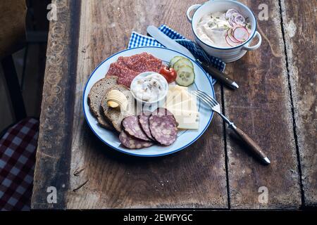 Hoher Winkel von köstlichen Wildwurst und Käse Scheiben mit Butter auf Roggenbrotstücken auf dem Teller Stockfoto