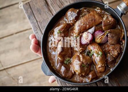 Von oben der Ernte anonymen Koch zeigt Gulasch mit appetitlich Geschmorte Fleischstücke und rote Zwiebel in der Pfanne schneiden Stockfoto