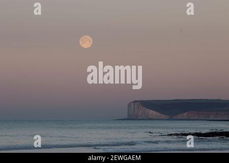 Monduntergang über Seaford Head und die sieben Schwestern vom Strand von Birling Gap an der Ostküste von Sussex im Südosten Englands Stockfoto