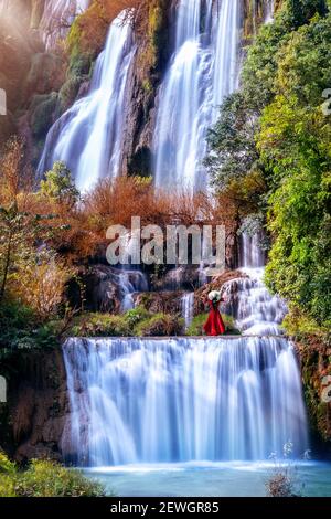Schönes Mädchen in rotem Kleid am Thi Lo Su Wasserfall (Tee Lor Su) in der Provinz Tak. Thi Lo Su Wasserfall der größte Wasserfall in Thailand. Stockfoto