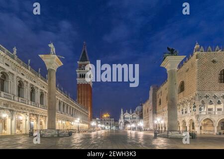 Morgendämmerung am Wasser in der Nähe des Markusplatzes, des Campanile und des Dogenpalastes, historischer Gebäude und Straßenlaternen. Stockfoto