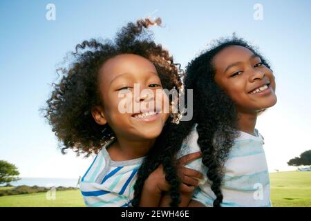 Junge gemischte Rasse Mädchen geben ihrem jüngeren Bruder ein Huckepack Aufzug Stockfoto