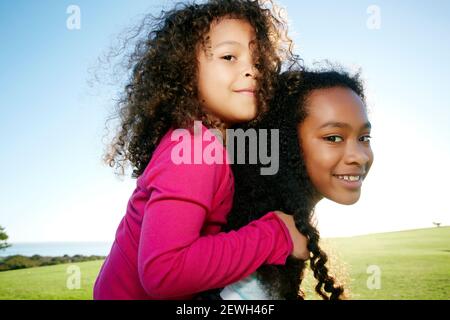 Junge gemischte Rasse Mädchen geben eine jüngere Schwester ein Huckepack Stockfoto