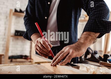 Zimmermann macht Bleistiftspuren auf einem Holzbrett Stockfoto