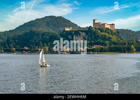 Blick auf die Rocca di Angera mit im Vordergrund ein weißes Segelboot auf dem Lago Maggiore, Italien Stockfoto