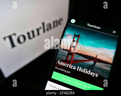 Handy mit Webseite des deutschen Online-Reisebüros Tourlane GmbH auf dem Bildschirm vor Firmenlogo. Fokus auf der Mitte des Telefondisplays. Stockfoto
