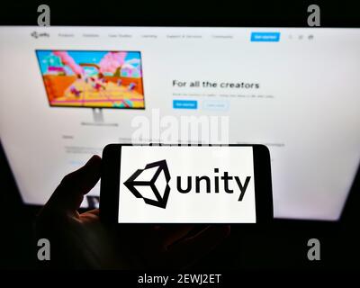 Person, die Smartphone mit Logo der US-Videospielfirma Unity Software Inc. Auf dem Bildschirm vor der Website hält. Konzentrieren Sie sich auf die Telefonanzeige. Stockfoto