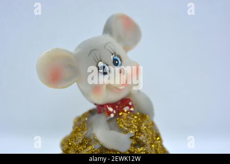 Keramik-Statuette einer niedlichen grauen Maus mit großen Ohren, die in einem Haufen von brassenden Goldmünzen steht. Stockfoto