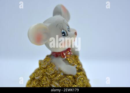 Keramik-Statuette einer niedlichen grauen Maus mit großen Ohren, die in einem Haufen von brassenden Goldmünzen steht. Stockfoto