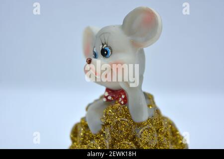 Keramik-Statuette einer niedlichen grauen Maus mit großen Ohren, die in einem Haufen von brassenden Goldmünzen steht. Stockfoto