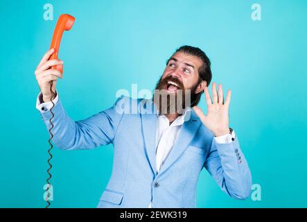 Schöner kaukasischer Geschäftsmann mit trendiger Frisur in Jacke sprechen auf Vintage-Telefon, Hallo. Stockfoto