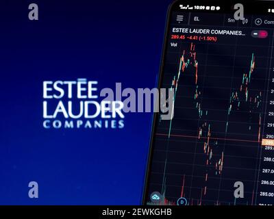 In dieser Abbildung werden die Börseninformationen der Estee Lauder Companies Inc. Auf einem Smartphone angezeigt, während das Logo der Estee Lauder Companies Inc. Als Hintergrund angezeigt wird Stockfoto