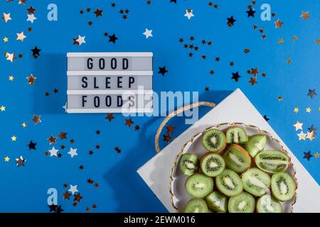 Ein Tablett mit reifen geschnittenen Kiwi auf blauem Hintergrund mit Sterne neben der Inschrift von guten Schlaf Lebensmittel Stockfoto