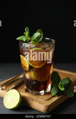 Tafel mit Glas Cuba Libre vor dunklem Hintergrund Stockfoto