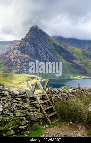 Stile über einer trockenen Steinmauer mit Blick auf Mount Tryfan und Llyn Ogwen See auf Fußweg zu den Carneddau Bergen In Snowdonia National Park Ogwen Wales Großbritannien Stockfoto