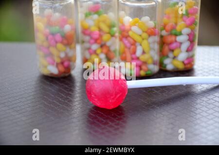 Der rosa Lollypop mit süßen Anisbohnen bunte Plastikflasche auf braunem Hintergrund. Stockfoto