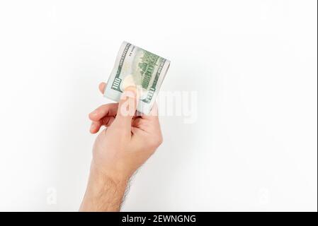 Unerkennbarer reifer Mann, der US-Dollar-Scheine isoliert auf weißem Hintergrund hält. Bündel von zusammengerollten Dollarscheinen, die in der Hand des kaukasischen Mannes geklammert wurden. C Stockfoto