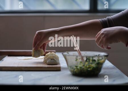 Nahaufnahme Hand machen Knödel. Traditionelle chinesische Küche während des chinesischen Neujahrs. Chinesisches Kulturkonzept Stockfoto