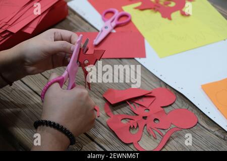 Chinesische Volkskunst des Papierschneidens. Nahaufnahme Hand halten Schere schneiden rotes Papier zu feiern chinesischen Neujahr. Stockfoto