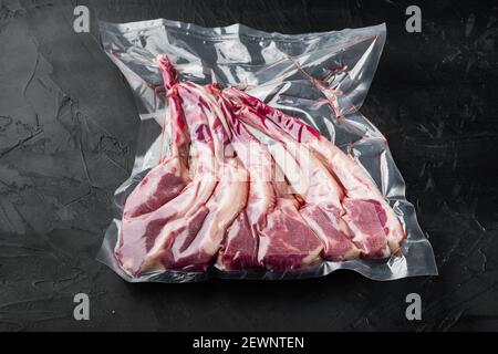 Lammrippe vakuumversiegelt bereit für sous vide Kochen Set, auf schwarzem Stein Hintergrund Stockfoto