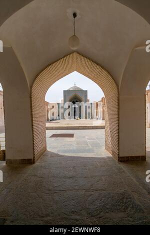 Yazd, Iran - 13,04.2019: Innenhof der historischen Jameh Moschee von Yazd mit seinen sechseckigen und türkisfarbenen Fliesen. Menschen, die im Hof von Shia gehen Stockfoto